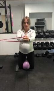 Technique for banded kneeling pallof press with rotation and ball squeeze.