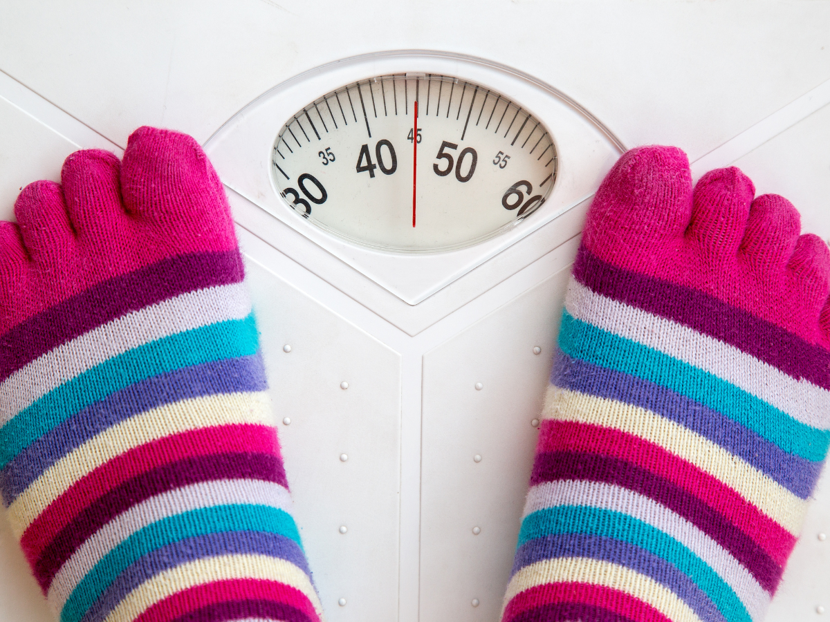 Standing on weight scale with colorful toe socks.